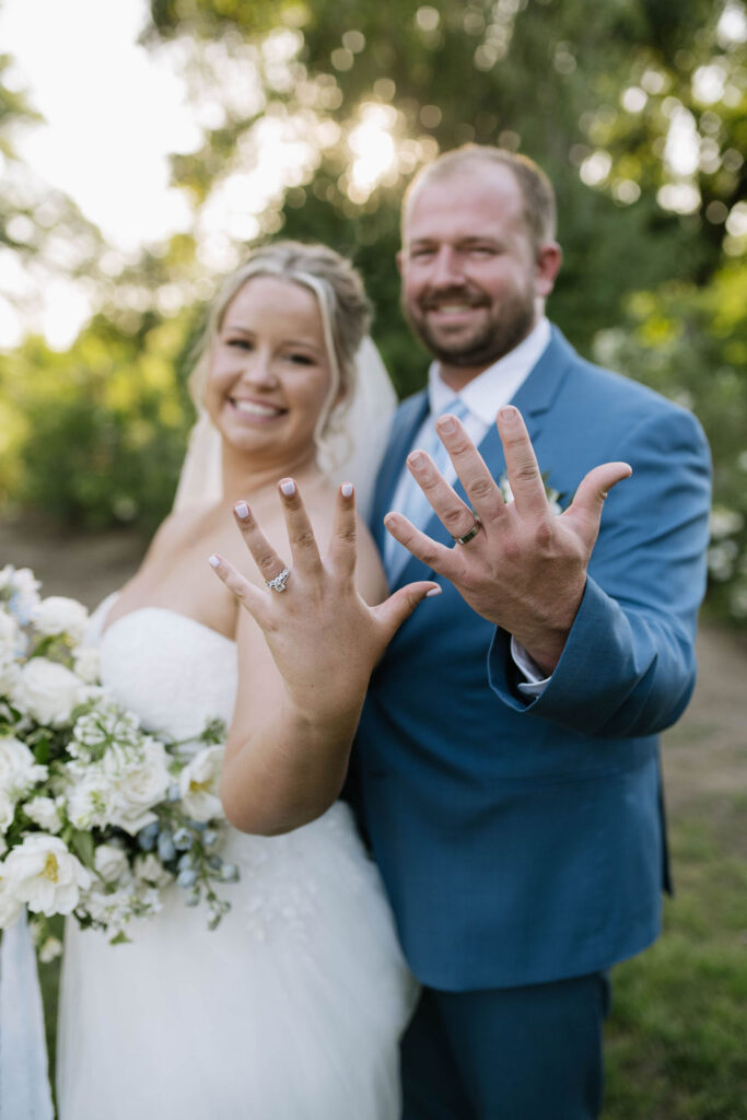 bride and groom showing their stunning wedding rings