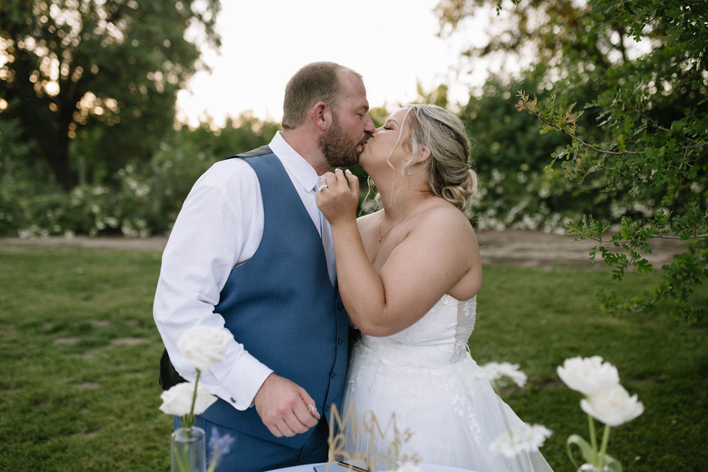 bride and groom kissing after cutting their wedding cake