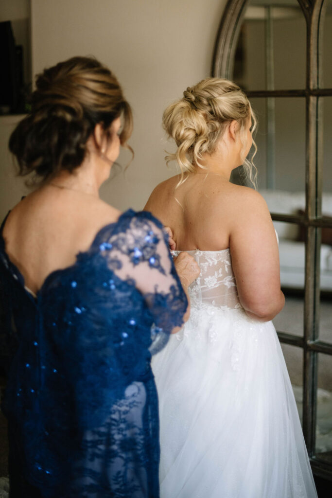 mother of the bride helping her with her wedding dress