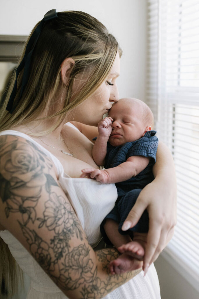 mom kissing her newborn on the forehead 