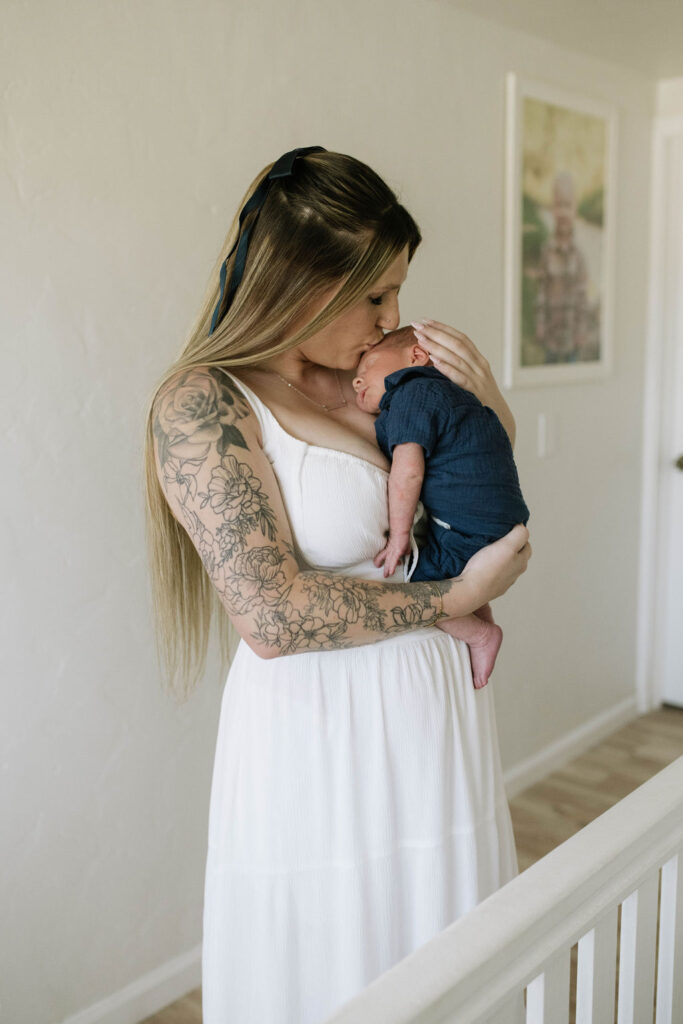 mother kissing her newborn baby at their intimate in-home newborn session