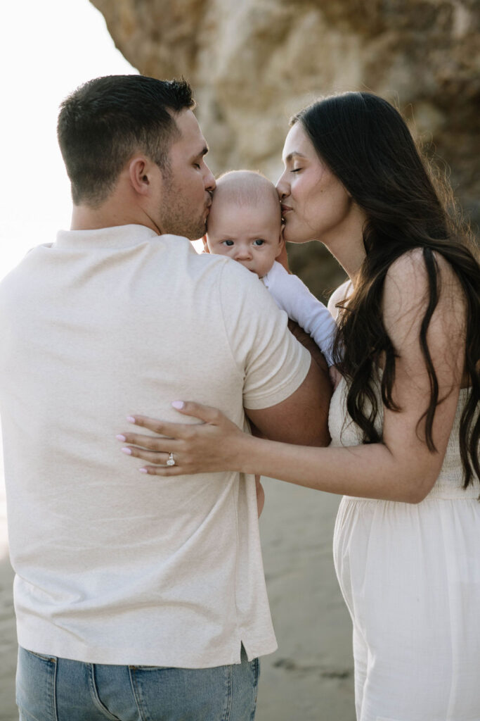 mom kissing his newborn on the forehead