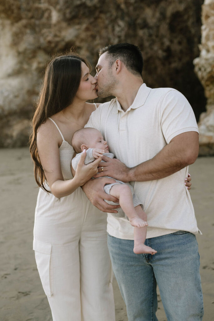 couple kissing at their beach family photoshoot